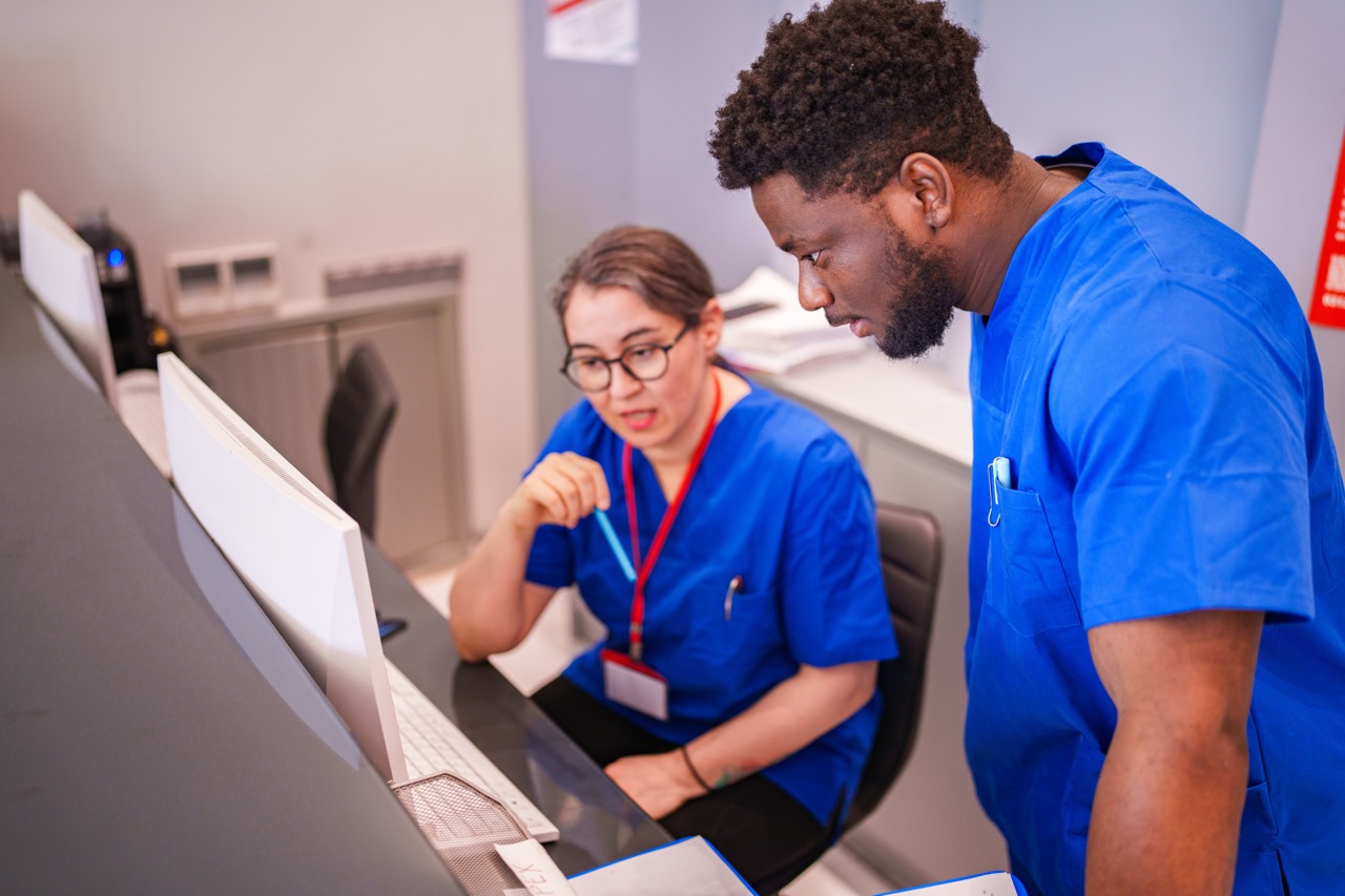 Two medical professionals in a clinical environment looking at results on a computer screen. 
